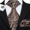A close-up of a men's silk jacquard tie featuring an intricate paisley pattern worn with a black suit jacket.