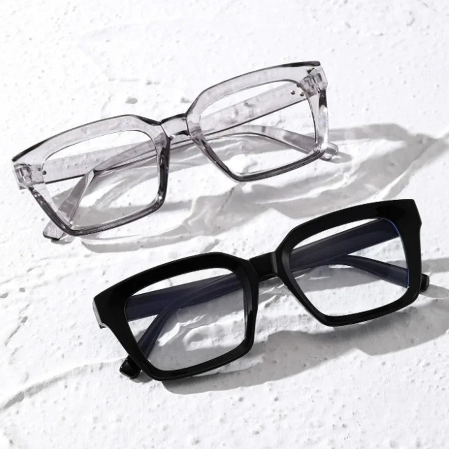 A pair of clear, square-framed reading glasses resting on a white textured surface.