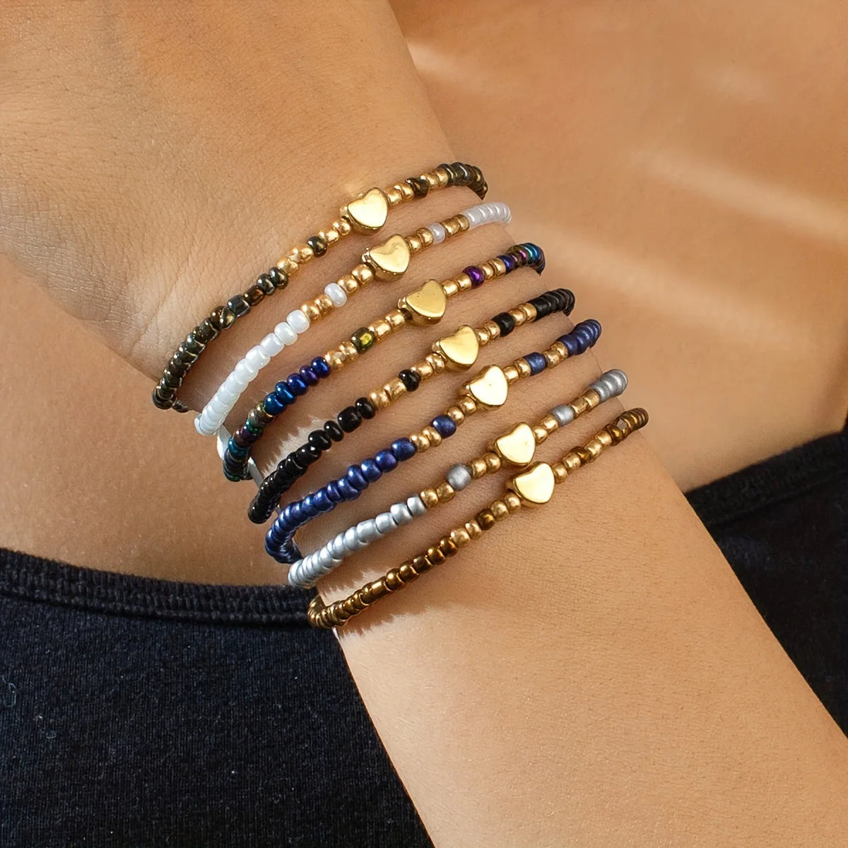 A set of bohemian resin beaded bracelets on a wrist, featuring various colors and gold accents.