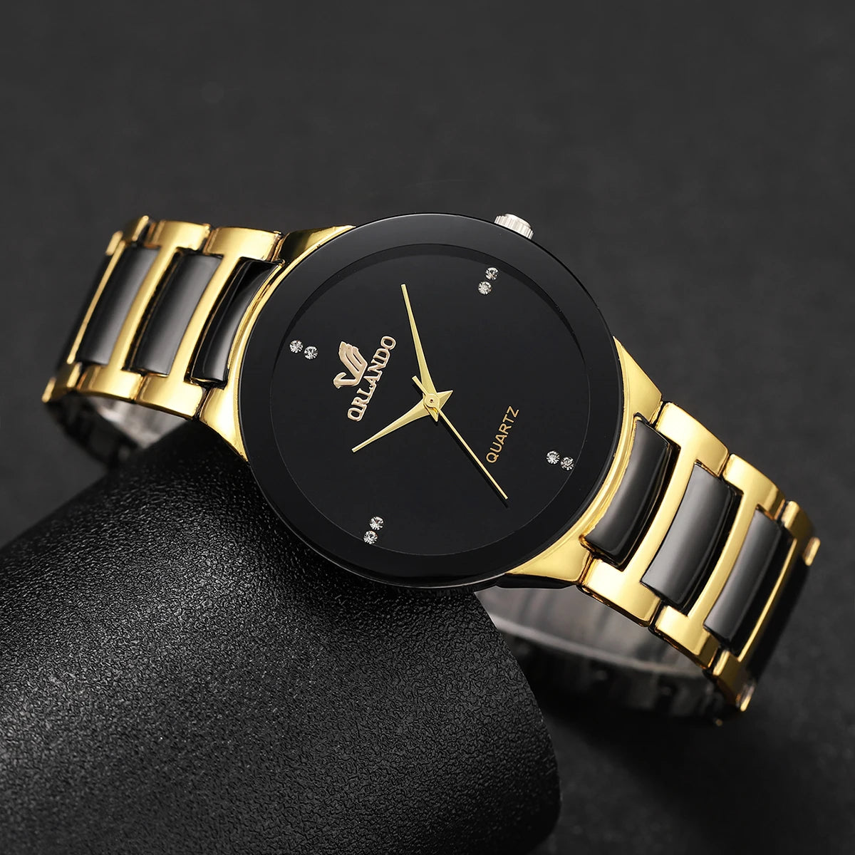 A black and gold couple's analog quartz watch set displayed on a dark surface.