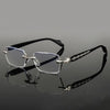 A pair of clear framed eyeglasses with silver accents resting on a dark reflective surface.
