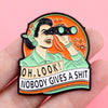 An enamel pin featuring a stylized character looking through a telescope against an orange background.