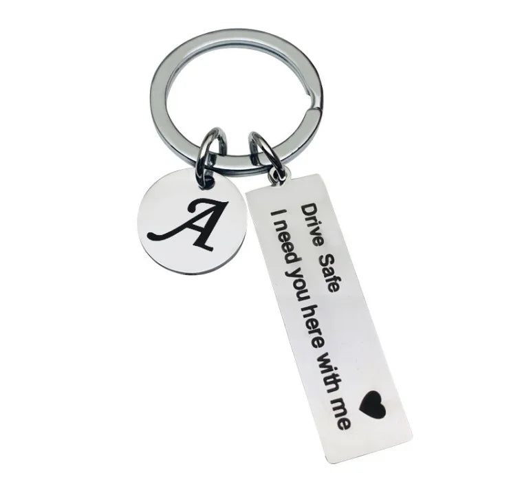 Silver keychain with an initial A and the message Drive Safe I need you here with me