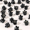 A set of black mini flower hair clips scattered on a white background.