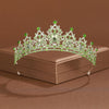 A sparkling crystal baroque bridal tiara with green stones and a central diamond set on a brown box.