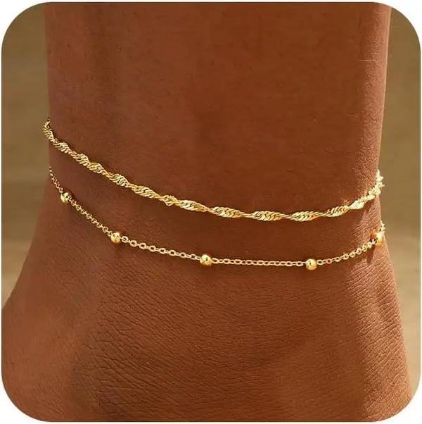 Gold plated beaded anklets worn on a person's ankle.