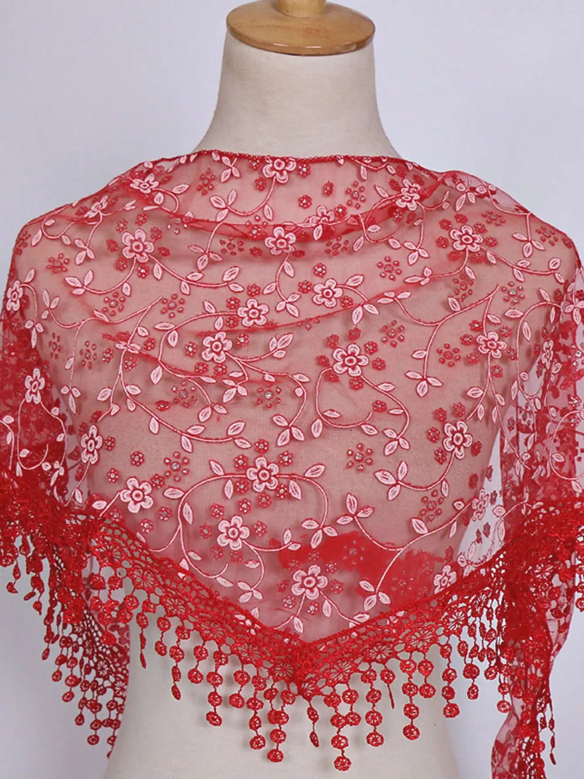 A sheer red floral lace scarf draped over a mannequin's neck and shoulders.