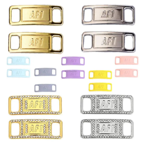 A collection of gold and silver metal shoe charms and laces with various finishes and designs.