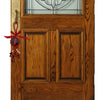 A wooden cross pendant with a red ribbon hangs on a dark wood door.
