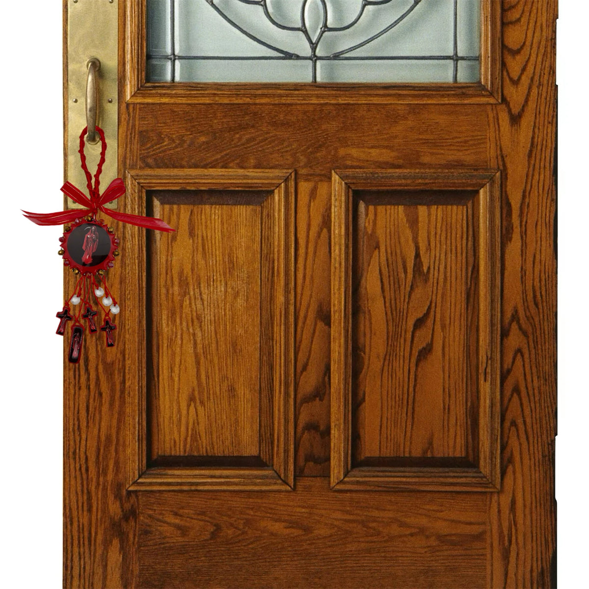 A wooden cross pendant with a red ribbon hangs on a dark wood door.