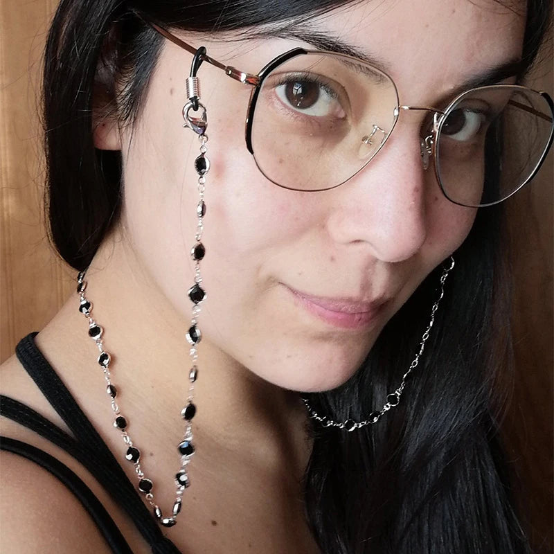 Una mujer vistiendo gafas de montura redonda con un collar de cuentas de cristal.