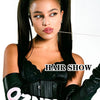 A model with long black hair extensions wearing a black outfit and black gloves.