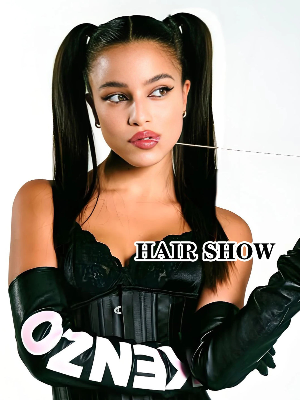 A model with long black hair extensions wearing a black outfit and black gloves.