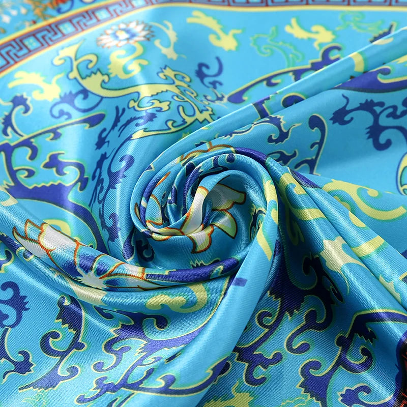 A vibrant blue silk scarf featuring intricate purple and yellow ornamental patterns.