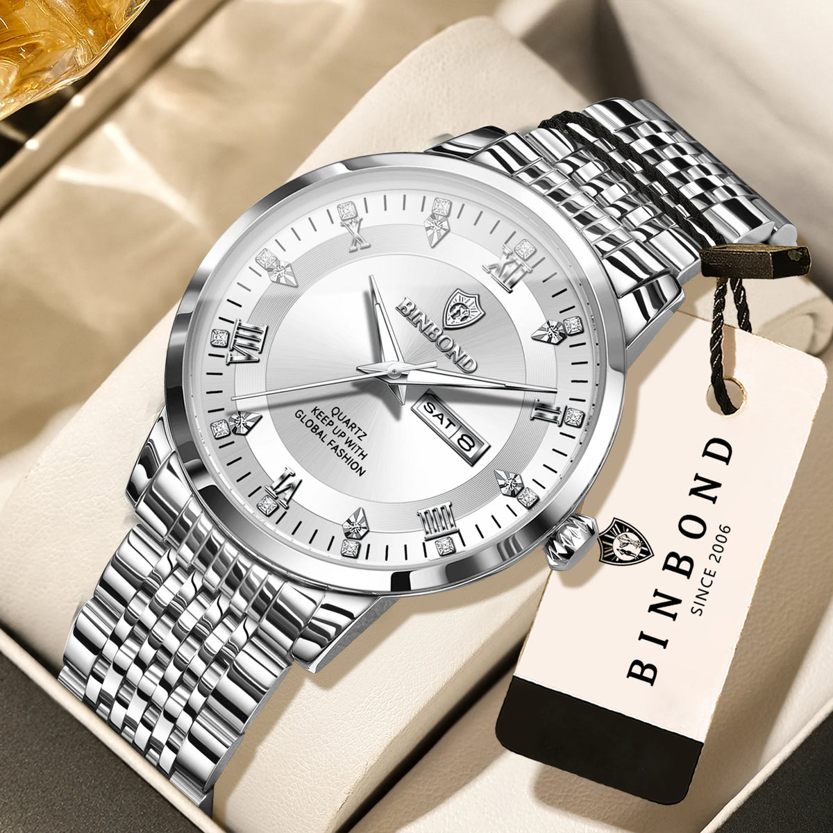 A silver and gold windup watch with a metal bracelet is displayed on a light-colored box.