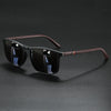 A pair of classic square sunglasses with dark lenses and a brown patterned frame resting on a dark surface.