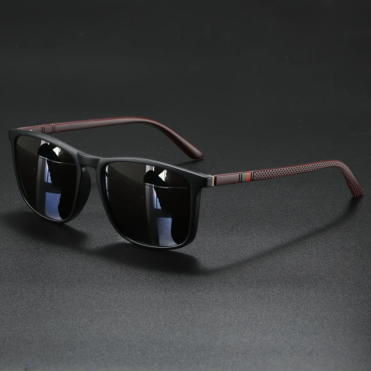 A pair of classic square sunglasses with dark lenses and a brown patterned frame resting on a dark surface.