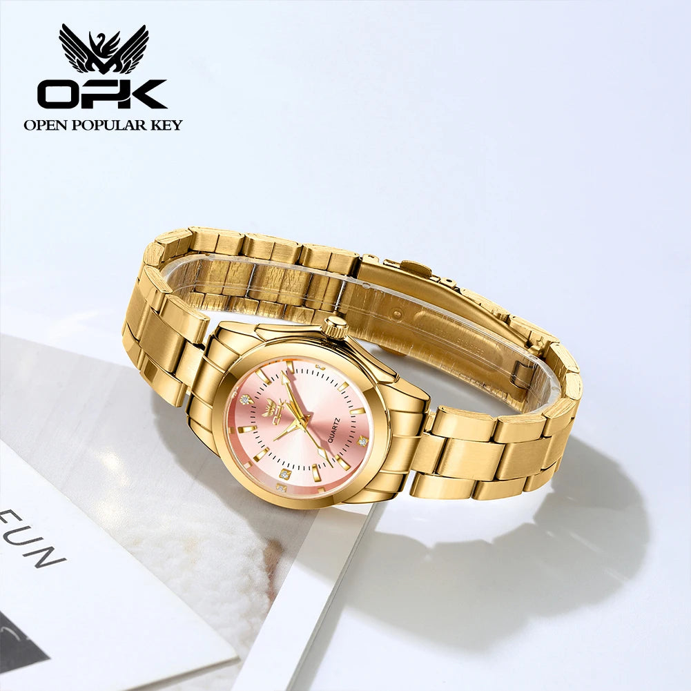 A gold-toned luminous quartz watch with a pink dial and gold casing is displayed on a white background.