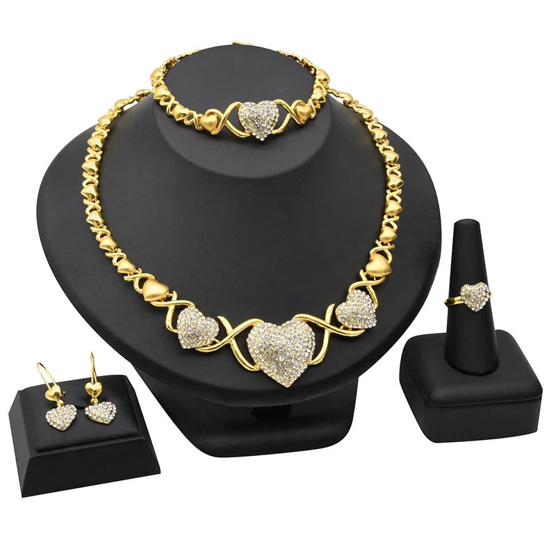 A gold heart crystal jewelry set featuring a necklace and ring displayed on a black stand.