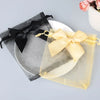 Two elegant drawstring gift bags, one black and one sheer yellow, with a gold ribbon detail.