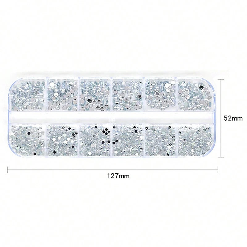 A rectangular plastic tray containing 12 small clear compartments filled with silver and black rhinestones for nail art decor