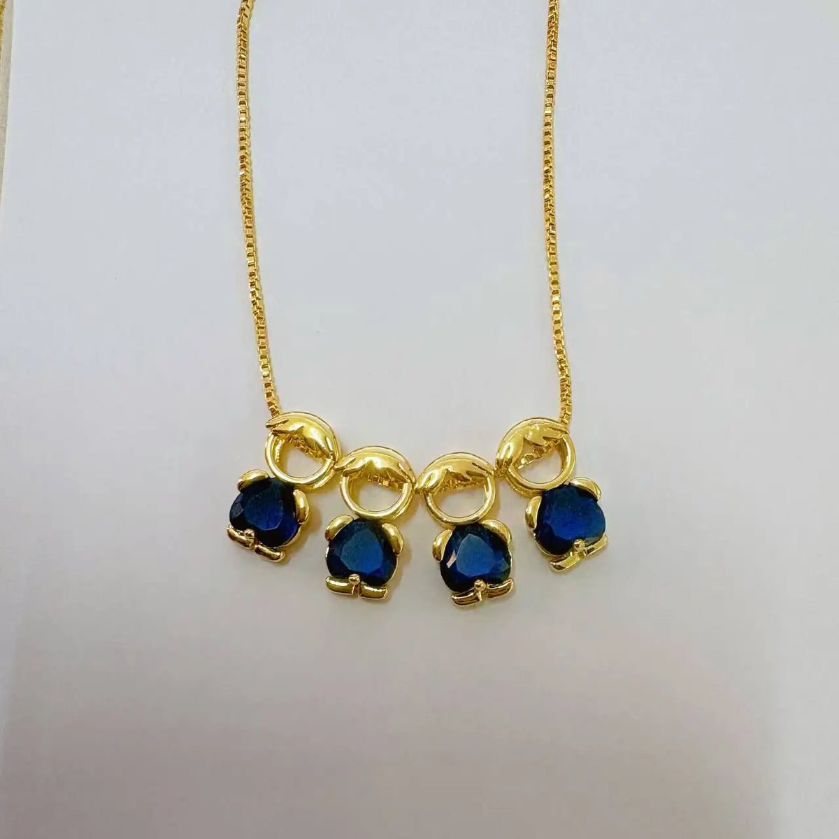 Goldkette mit drei blauen Edelstein-Herzanhängern.