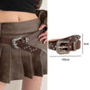A dark brown leather belt with silver bullet studs and a decorative buckle worn over a pleated skirt.