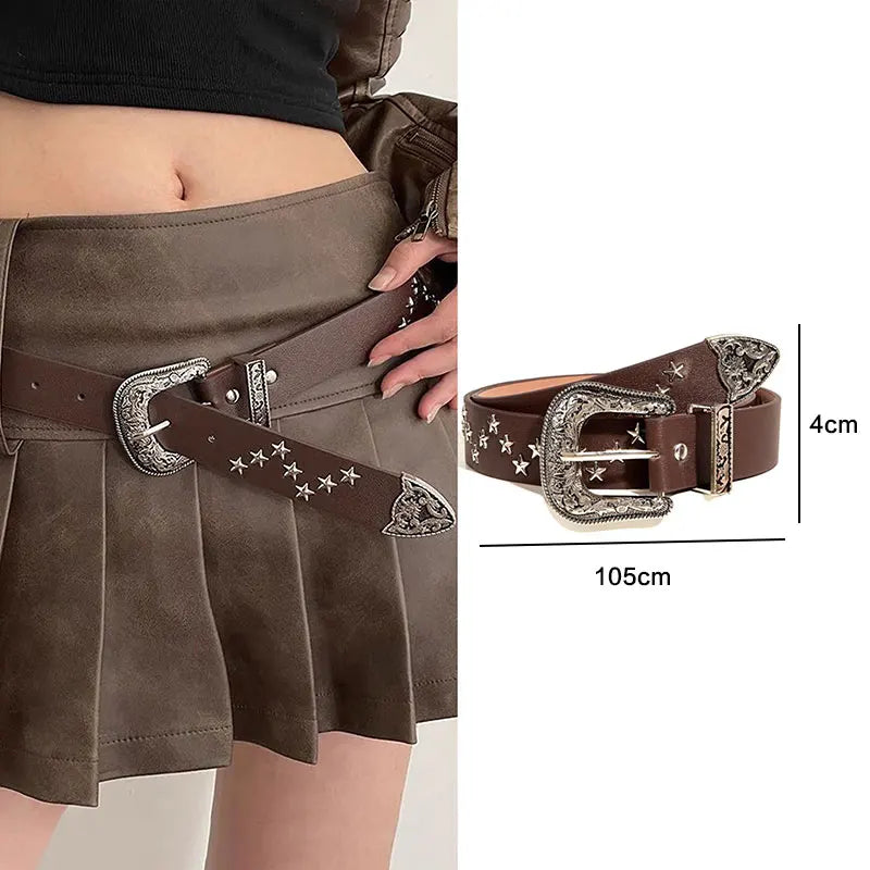 A dark brown leather belt with silver bullet studs and a decorative buckle worn over a pleated skirt.