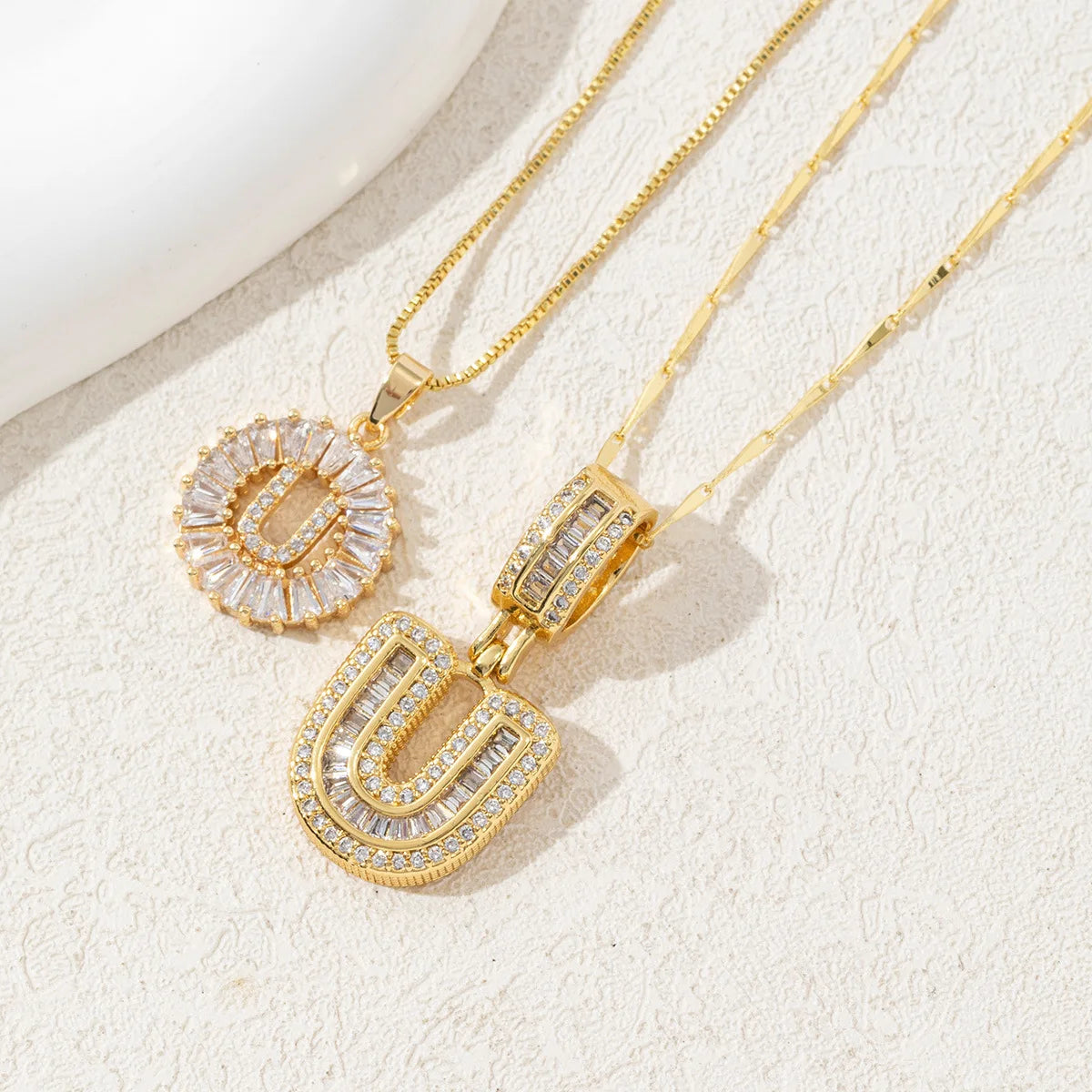 Gold-toned necklace set featuring CZ crystal pendants shaped like the letters U and a circular design.