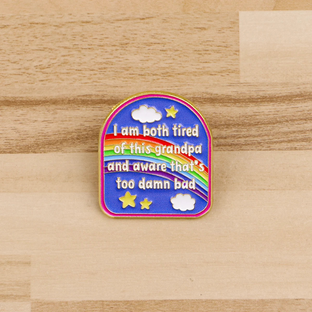 A colorful enamel pin featuring text that says I am both tired of this grandpa and aware that's too damn bad