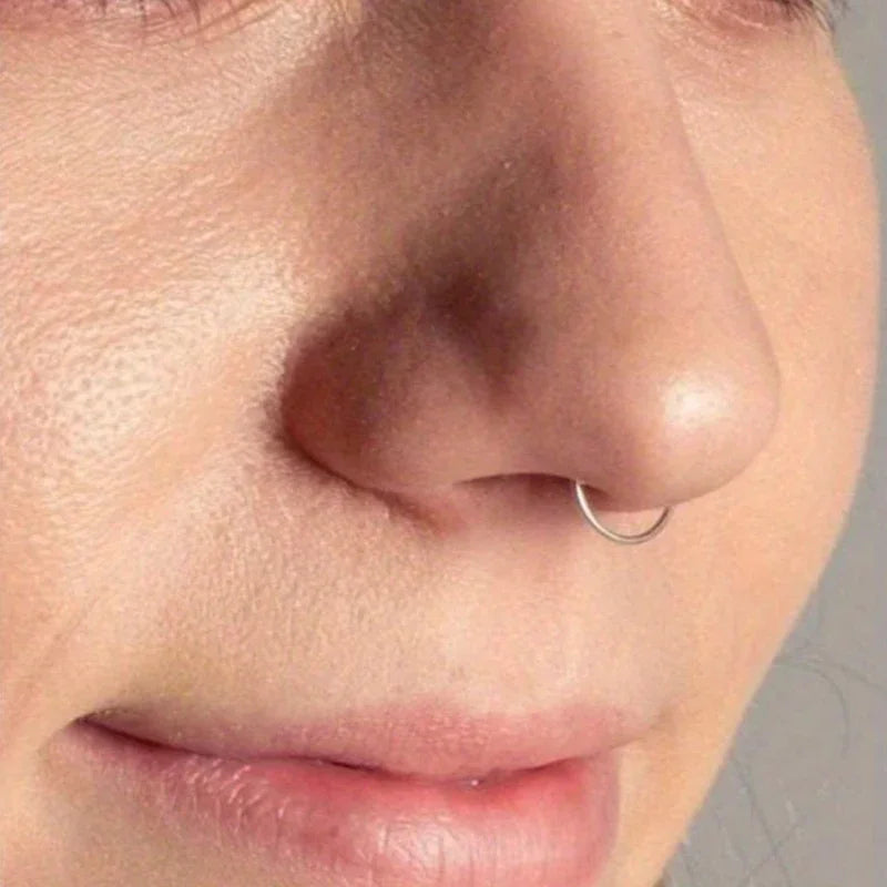 A close-up of a person's nose showing a small silver hoop earring.