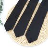Three black neckties laid diagonally on a woven straw mat.