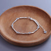 Sterling silver double heart charm bracelet displayed on a wooden dish