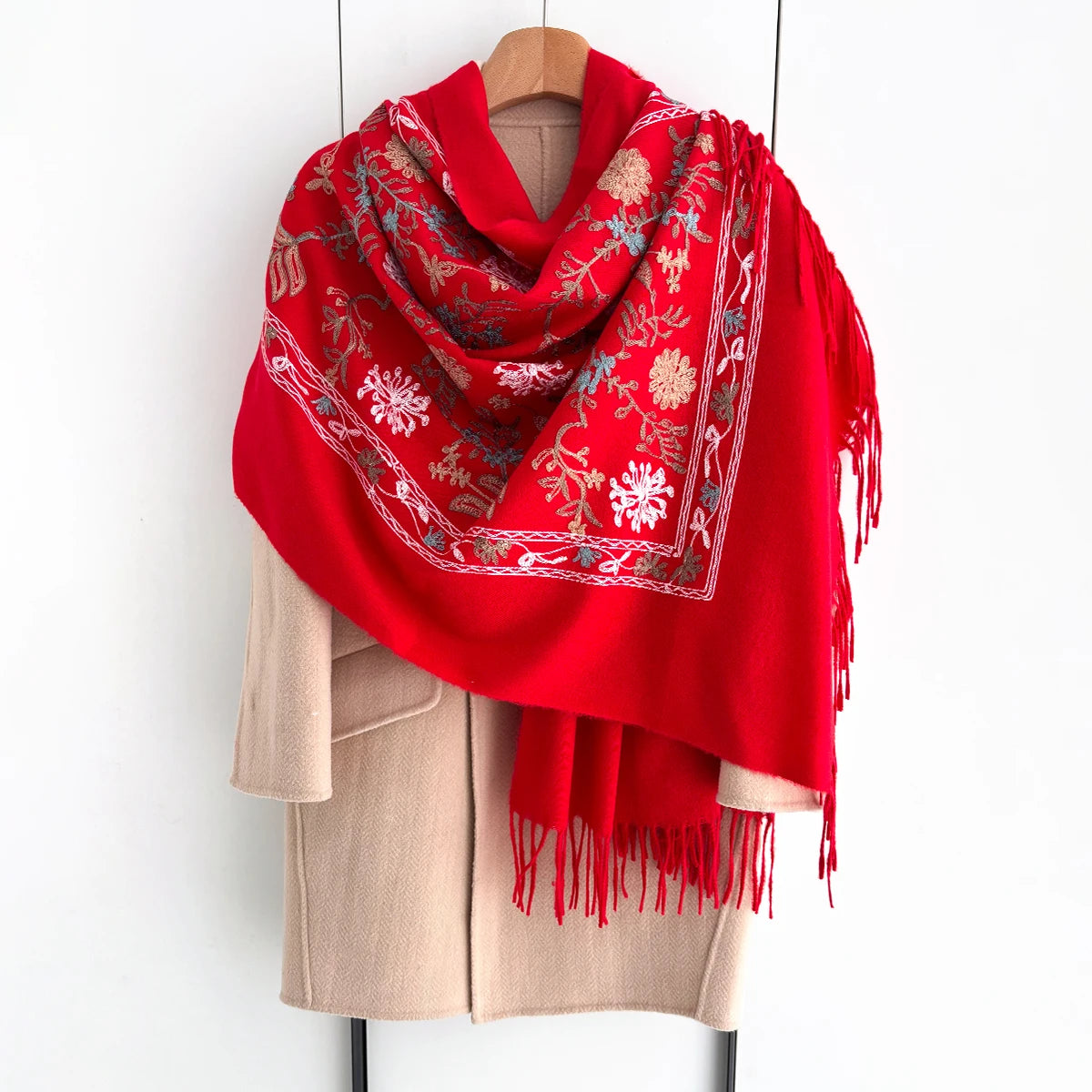 A vibrant red luxury floral scarf draped over a beige coat hanger.