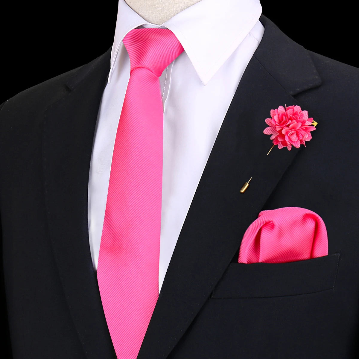 Chaqueta negra sobre camisa blanca y corbata de seda rosa brillante con una flor boutonnière rosa.