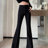 A woman models high-waist flare skinny black pants and a sheer black top in a bright indoor setting.