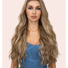 Una mujer modela extensiones de cabello ondulado clip-in de 22 pulgadas en un color rubio claro.