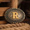 A vintage western belt buckle with an ornate gold design resting on a wooden surface.