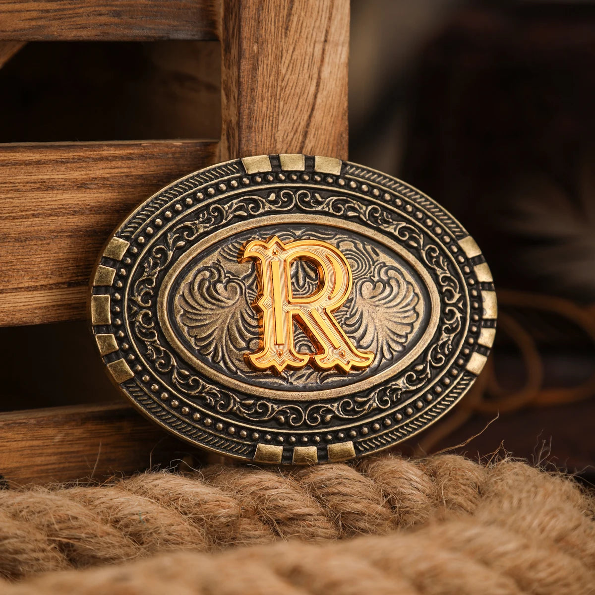 A vintage western belt buckle with an ornate gold design resting on a wooden surface.