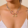 Collar de cuentas multicolor con dije inicial usado alrededor del cuello.