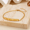 Gold stainless steel zodiac constellation charm bracelet lying on a light colored surface
