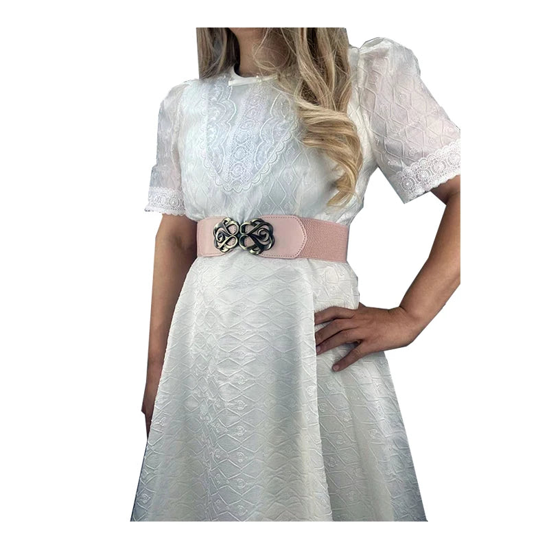White lace dress with sheer sleeves and a pink leather belt featuring a brass buckle