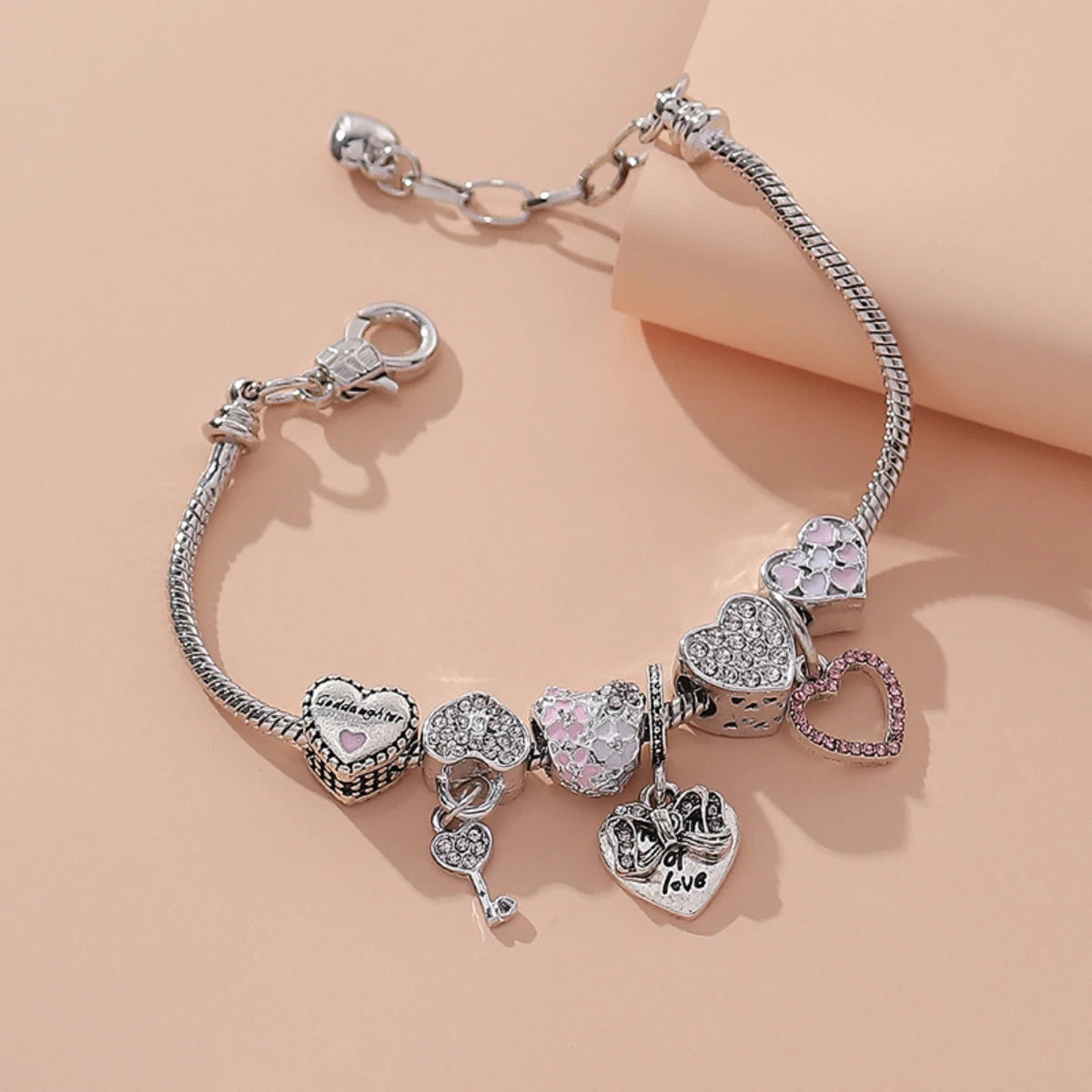 Silver beaded love bracelet set featuring multiple heart charms and chains on a beige background