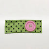 A pink fabric headband with black polka dots and a circular pink accent.