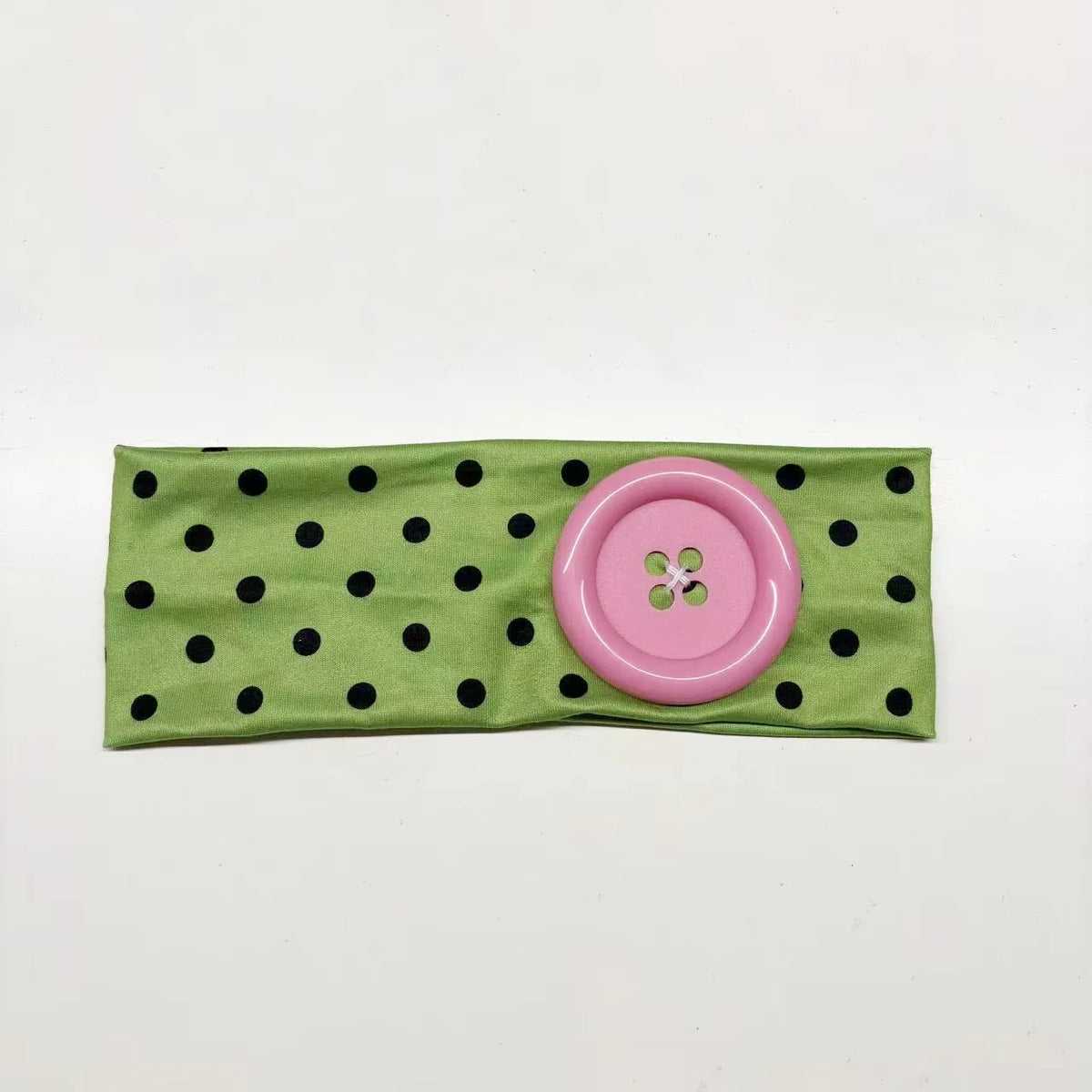 A pink fabric headband with black polka dots and a circular pink accent.