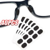 Un paquete de 40 almohadillas nasales reutilizables antideslizantes para gafas, junto a un par de gafas.