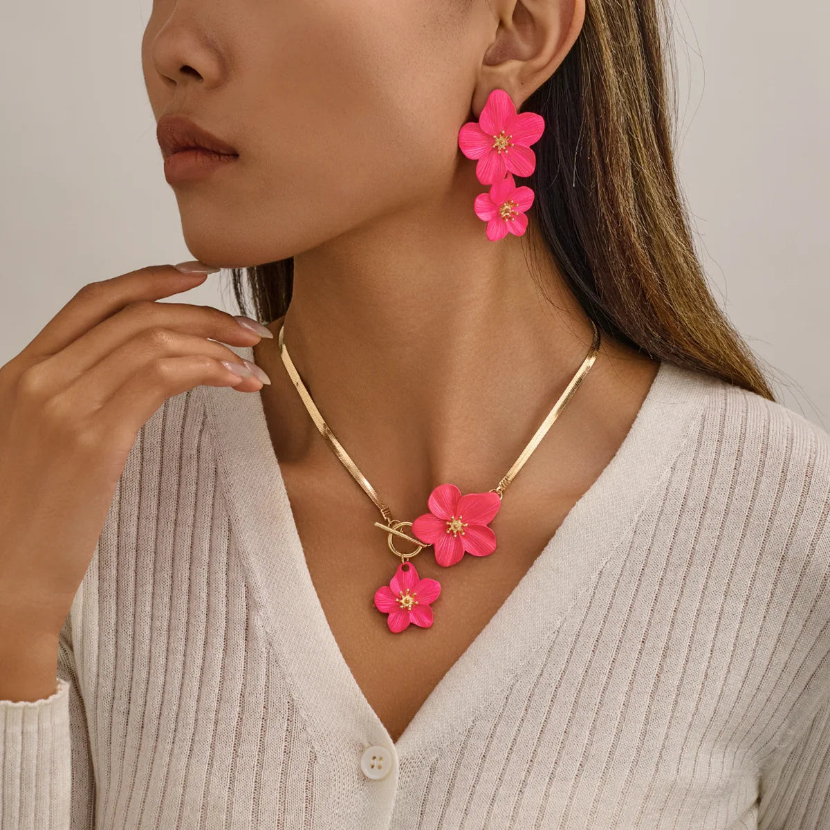 A close-up of a woman wearing a gold floral pendant necklace and matching earrings on her neck and ears.