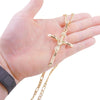 Eine Hand hält eine vergoldete Jesus-Kreuz-Anhänger-Kette vor weißem Hintergrund.