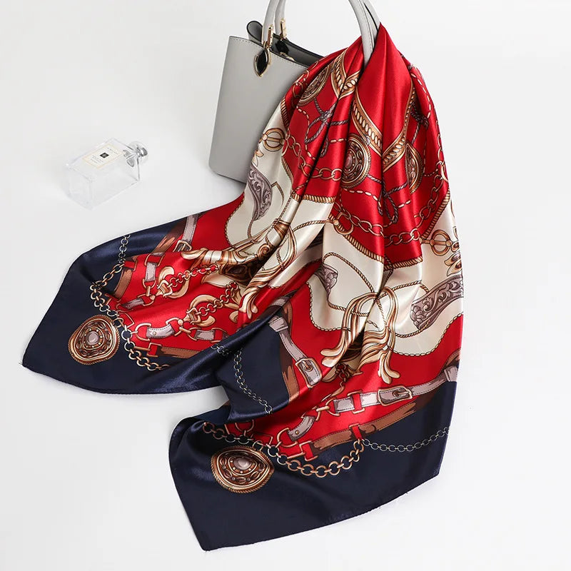 A large silk print shawl in red, gold, and cream patterns draped over a white surface.