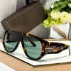 Brown tortoiseshell oversized pilot sunglasses resting on a light wooden surface.